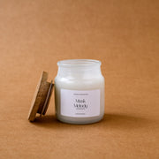 Glass jar candle labeled Musk Melody with cork lid on brown background
